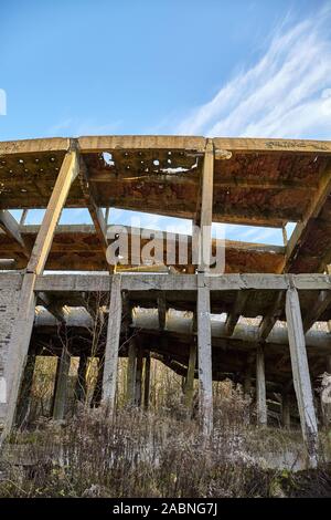 La structure industrielle de béton ruinée en forêt au coucher du soleil. Banque D'Images