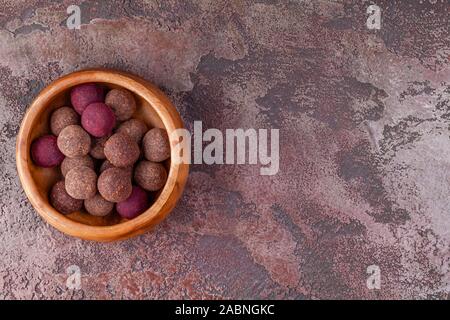 Des boules d'énergie Cacao Végétalien Premières dans bol en bois sur fond de marbre marron Banque D'Images