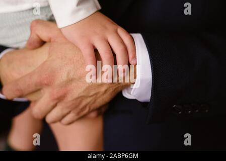 Close-up of child's mains reposant sur les poings de son père. Banque D'Images