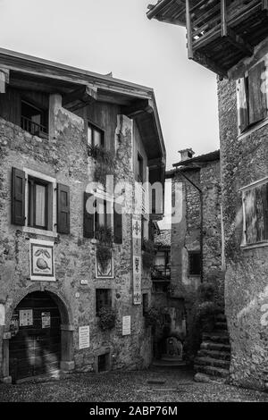 Via Francesco Baracca, la petite place principale du village médiéval de Canale di Tenno, Trentino-Alto Adige, Italie. Version noir et blanc Banque D'Images