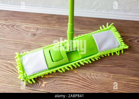 Plastique vert rdp sur un plancher en bois brun. Laver le plancher. L'entretien ménager et les tâches ménagères. Produits de nettoyage et d'équipement. Vue d'en haut. Banque D'Images