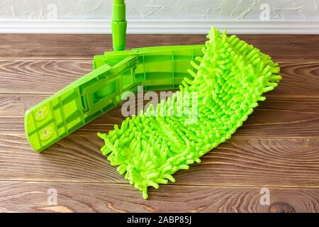 Mop verte sur un plancher en bois brun. Laver le plancher. L'entretien ménager et les tâches ménagères. Produits de nettoyage et d'équipement. Vue d'en haut. Banque D'Images