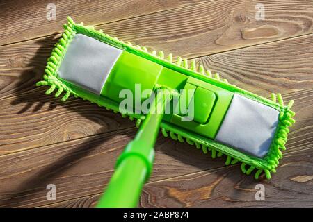 Le lavage avec un plancher en bois brun mop vert. L'entretien ménager et les tâches ménagères. Produits de nettoyage et d'équipement. Vue d'en haut. Banque D'Images