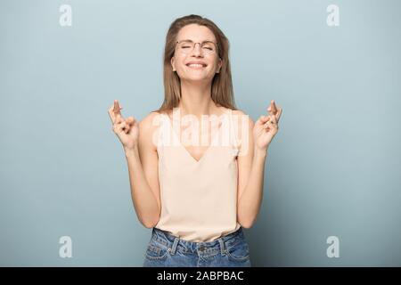 Jeune femme dans les verres crossing fingers souhaiter bonne chance Banque D'Images