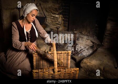 Portrait de la Renaissance dans le style de Rembrandt d'une jeune femme en costume paysan médiéval travaux près de la cheminée authentique d'un bien français parution Banque D'Images