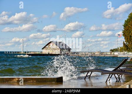 Vagues se briser sur un quai avec des chaises de se mouiller dans des vents violents en automne, Anderson l'entrepôt avec quai de graffitis dans la distance, Ephriam, WI, USA Banque D'Images