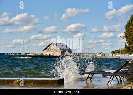 Vagues se briser sur un quai avec des chaises de se mouiller dans des vents violents en automne, Anderson l'entrepôt avec quai de graffitis dans la distance, Ephriam, WI, USA Banque D'Images