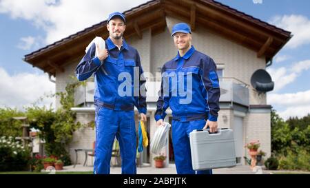 Portrait Of Smiling Young male Electrician debout en face de la maison avec des kits d'électricien Banque D'Images