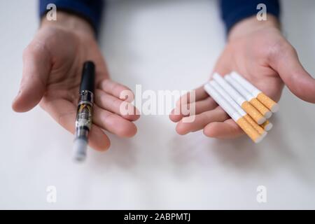 Man Holding Vape et plus de 24 cigarettes de tabac Banque D'Images