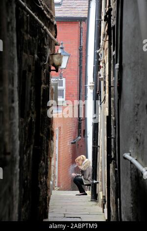 une jeune femme fume de manière alliée pour ne pas être vue, se cacher, comme elle prend une pause de son travail Banque D'Images