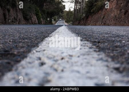 Dans la perspective de la route basse de l'asphalte avec une voiture à la distance Banque D'Images