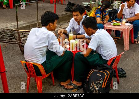 Un groupe de jeunes gens de manger un délicieux repas dans un Street Food, Yangon, Myanmar. Banque D'Images
