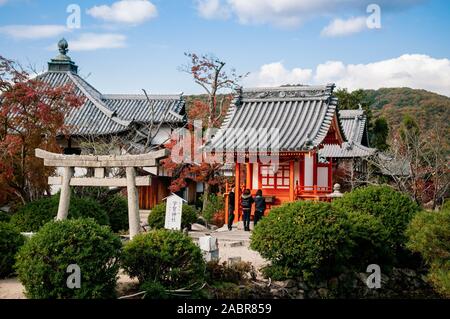 NOV 18, 2014 Okayama, Japon - Japonais Local woman praying at petit Uka culte dans jardin et Fugenin temple dans l'arrière-plan. Banque D'Images