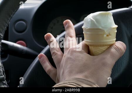 Man holding ice cream derrière le volant d'une voiture Banque D'Images