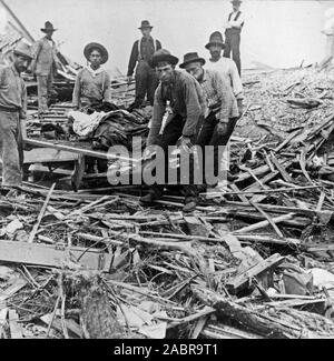 Les hommes exerçant son corps sur un brancard, entouré de débris de l'ouragan et des inondations, Galveston, Texas ca. Septembre 1900. Banque D'Images