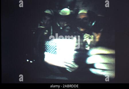 Teleclip - Projet d'essai Apollo-soyouz - Tom Stafford avec Alexei Leonov et Valeri Kubasov tenant le drapeau USA - à l'intérieur de la capsule Soyouz 19 quelques instants après l'arrimage avec Apollo CSM-111 - photo prise directement à partir de la télévision couleur écran dans le UK - par 'Harry' (le photographe inconnu) au cours de la diffusion en direct en juillet 1975. L'Apollo Soyouz Test Project-(ASTP) (Russe : Экспериментальный Аполлон "полёт" - "Союз" (ЭПАС Eksperimentalniy Apollon-Soyuz), polyot, allumé. Vol expérimental' 'Apollo-soyouz, communément appelé par les Soviétiques comme Apollo Soyouz-), menée en juillet 1975. Banque D'Images