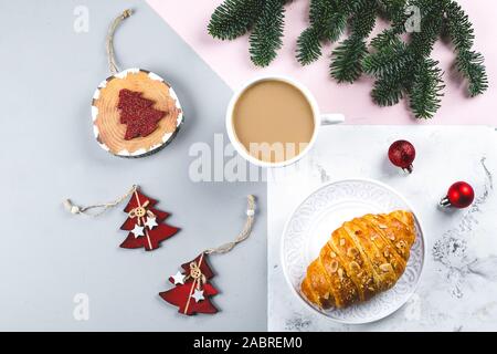 Petit-déjeuner de Noël. Tasse de café, des croissants et des jouets, décoration de sapin branches sur fond tricolore. table. Haut de la vue, télévision lay Banque D'Images