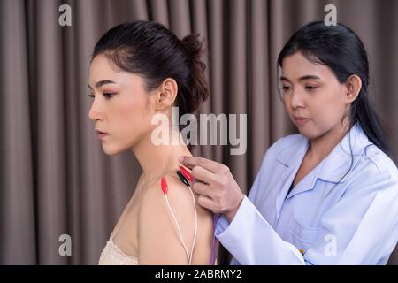 Jeune femme l'objet d'un traitement d'acupuncture avec stimulateur électrique sur l'épaule avec médecin Banque D'Images