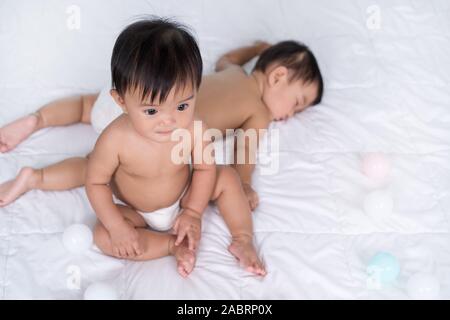 Lits bébés sur un lit, l'un assis, 1 Banque D'Images