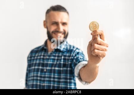 Homme barbu d'âge mûr portant chemise à carreaux élégant en tenant la main d'or en bitcoin et isolés sur fond gris Banque D'Images