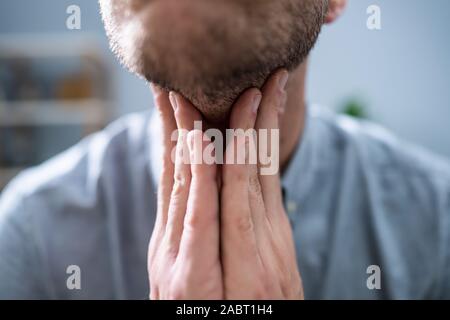 Close-up de la main d'un homme touchant ses maux de gorge Banque D'Images