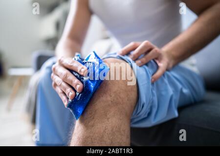 Close-up d'une personne assise à l'application de glace et de gel sur un genou blessé Banque D'Images