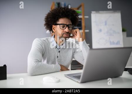 Sad Young Man working on Laptop At Desk Banque D'Images