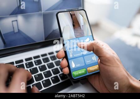 Close-up of a Businessman's Hand à l'aide de système de sécurité de la maison On Mobile Phone Banque D'Images