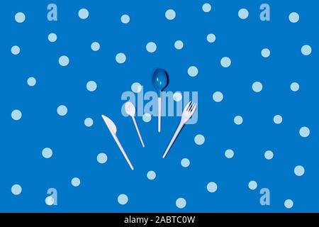 Concept de couverts jetables en plastique blanc sur fond bleu, entouré de cercles bleus. Mise à plat, vue du dessus. Banque D'Images