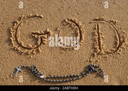 Rosaire et ehh nom de Dieu écrite dans le sable humide sur la plage. Banque D'Images