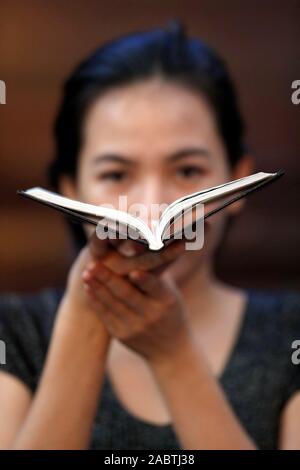 Femme catholique lire la bible à l'église. Hue. Le Vietnam. Banque D'Images