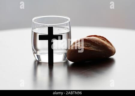 Croix chrétienne, verre d'eau, et la sainte Bible pendant le Carême. Une solennelle célébration religieuse qui commence le mercredi des Cendres et se termine le samedi saint. Banque D'Images