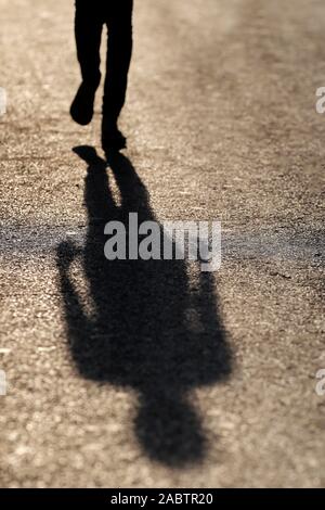 Femme marche et projection d'ombre sur la rue. Hanoi. Le Vietnam. Banque D'Images