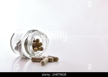 Pot en verre rempli de capsules de médicaments sur la table blanche et fond isolé. Vue de face. Composition horizontale. Banque D'Images