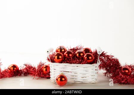 L'angle faible copie espace Noël : peu défraîchies white panier plein de boules de Noël rouge avec décoration rouge couronne sur table en bois clair et blanc ba Banque D'Images