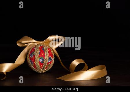 Noël en bois sombre copie espace : decoupage noël isolés ball close up avec de l'or en ruban de satin noir fond Banque D'Images
