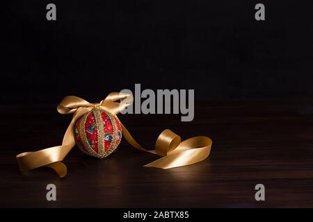 Noël en bois sombre copie espace : decoupage noël isolés ball close up avec de l'or en ruban de satin noir fond Banque D'Images