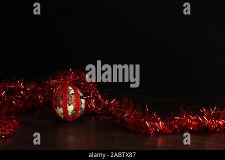 Noël en bois sombre copie espace : decoupage noël isolés ball close up avec guirlande décorative en ruban rouge fond noir Banque D'Images