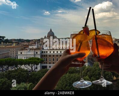 Un couple est maintenant verres d'Aperol dans le bar à l'intérieur du Château Sant'Angelo. Verres d'Aperol et la basilique St Pierre à l'arrière-plan. Banque D'Images