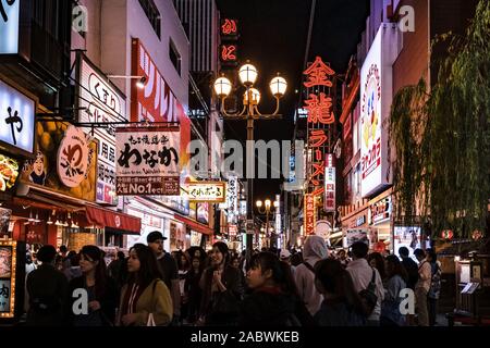 Foule de touristes flânant dans l'un des rues dans la région d'Osaka Dotonbori. Cityscape par nuit avec beaucoup de panneaux et de feux. Banque D'Images