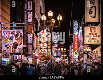 Foule de touristes flânant dans l'un des rues dans la région d'Osaka Dotonbori. Cityscape par nuit avec beaucoup de panneaux et de feux. Banque D'Images