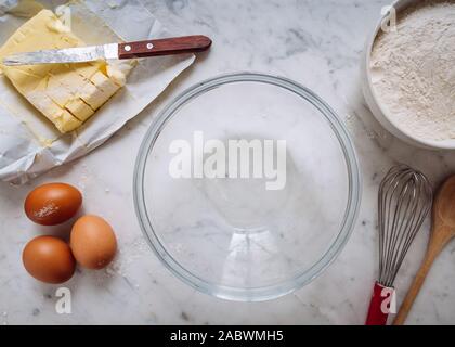 Pâtisserie Maison arrière-plan. Outils de pâtisserie et les ingrédients sont sur la table de marbre blanc. Le beurre, les oeufs, la farine, le verre bol vide et fouet de cuisine Banque D'Images