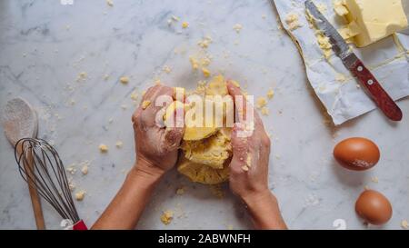 Faire la pâte, caucasian woman mains faire une pâte avec la farine les oeufs et le beurre. pâtisserie maison. fond blanc Banque D'Images