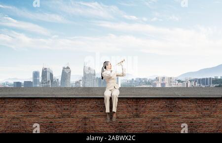 Attractive young woman playing trumpet sur toit Banque D'Images