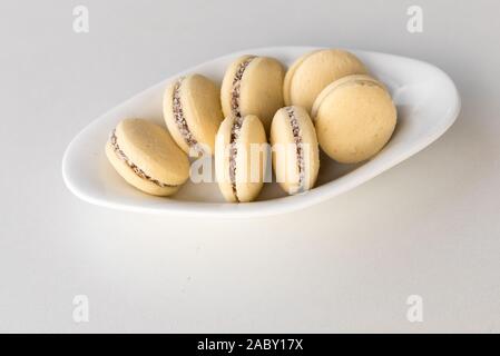 Macarons vanille blanc sur fond de bois. Dessert délicat française pour le petit déjeuner dans la lumière matinale. De délicieux cookies argentin alfajores avec de la crème sur une assiette sur la table. Vue d'en haut. Banque D'Images