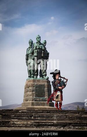 Un joueur de cornemuse joue en face de la statue commémorative de commando de la DEUXIÈME GUERRE MONDIALE à Spean Bridge, commandée en 1949 par le sculpteur Scott Sutherland. Banque D'Images