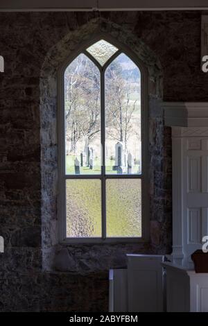 Vue sur le cimetière par une fenêtre de l'église Saint-Clachan. L'église date de 1817. Banque D'Images