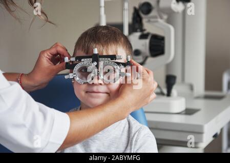 Médecin porter des lunettes pour un enfant. Petit garçon avec phoropter dont il les yeux dans le cabinet du médecin Banque D'Images