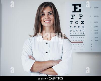 Photo de belle femme ophtalmologiste debout dans l'arrière-plan de la carte avec des lettres Banque D'Images