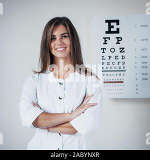 Un design époustouflant. Photo de belle femme ophtalmologiste debout dans l'arrière-plan de la carte avec des lettres Banque D'Images